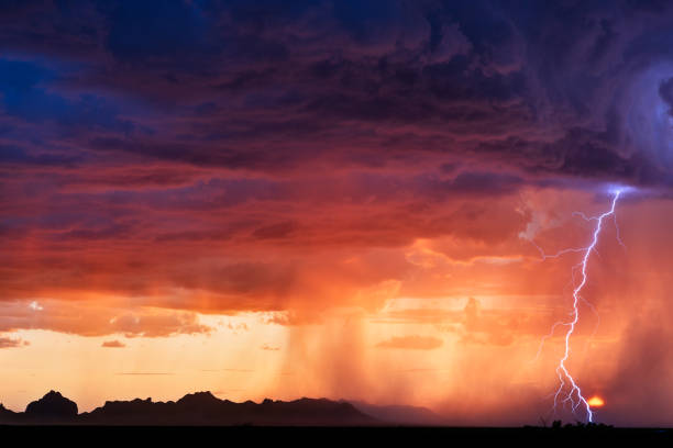 Lightning bolt from a thunderstorm A lightning bolt strikes next to the setting sun as a thunderstorm moves through the desert near Salome, Arizona. lightning thunderstorm electricity cloud stock pictures, royalty-free photos & images