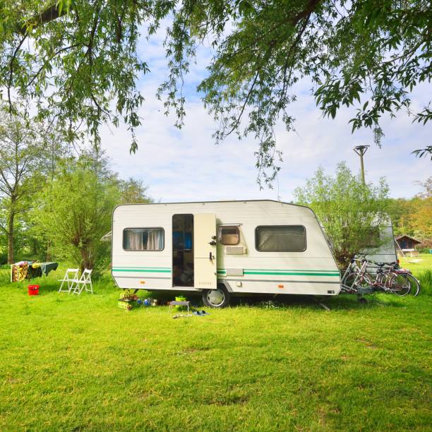 istock Caravan trailer camping on a green lawn under a tree in springtime 1176380512
