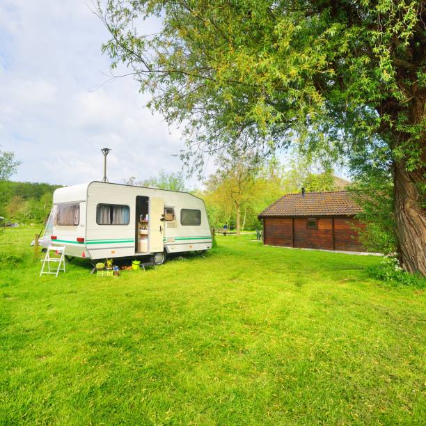 istock Caravan trailer camping on a green lawn under a tree in springtime 1176380515