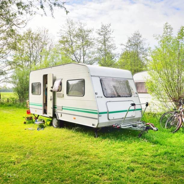 istock Caravan trailer camping on a green lawn under a tree in springtime 1176380516