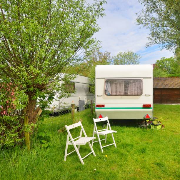 istock Caravan trailer camping on a green lawn under a tree in springtime 1176380517