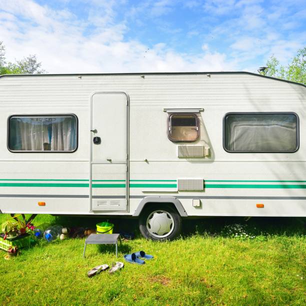 istock Caravan trailer camping on a green lawn under a tree in springtime 1176380527