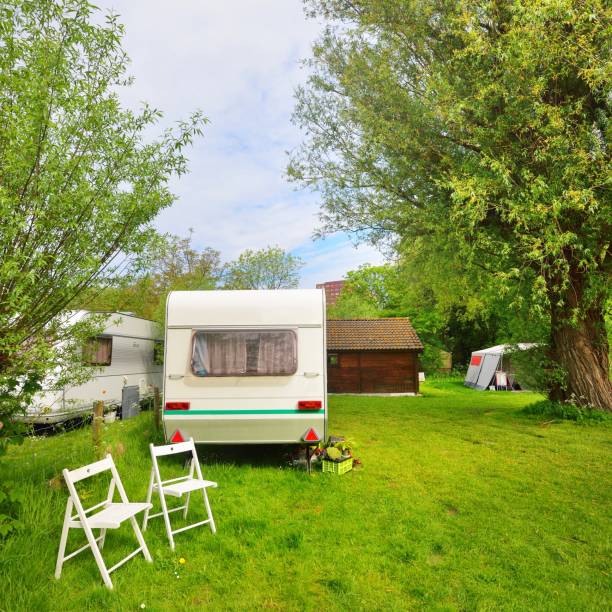 istock Caravan trailer camping on a green lawn under a tree in springtime 1176380542