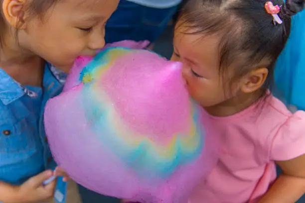 Happy children boy and girl brother and sister eating cotton candy.  High resolution image gallery.