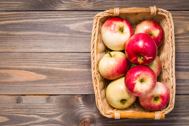 istock Ripe red apples in a basket on a wooden table. Top view 1176394577