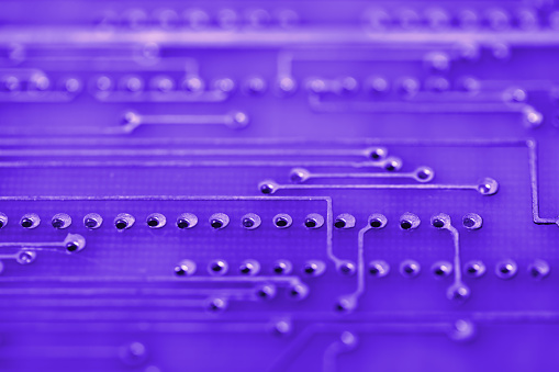 Close-up photo of an electronic circuit board in purple tones with copy space. Shallow depth of field. Can be used as a background.