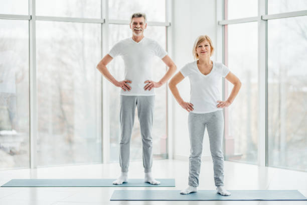pronto per iniziare l'allenamento. bella coppia di anziani in piedi in una spaziosa sala fitness bianca prima di una sessione sportiva. - coppia eterosessuale foto e immagini stock