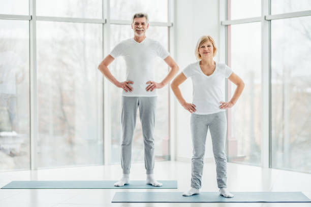 pronto para começar a treinar. pares idosos bonitos que estão em uma sala de fitness branca espaçosa antes de uma sessão do esporte. - casal heterossexual - fotografias e filmes do acervo