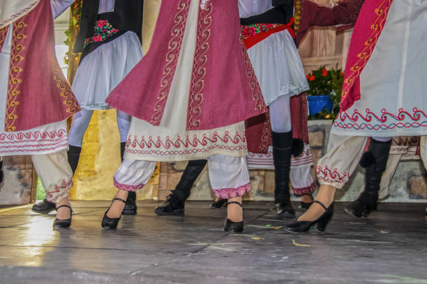 vue cultivée des danseurs grecs sur l'étape dans le beau costume brodé avec des femmes devant des hommes - jambes et pieds - flou de mouvement - tradition grecque photos et images de collection