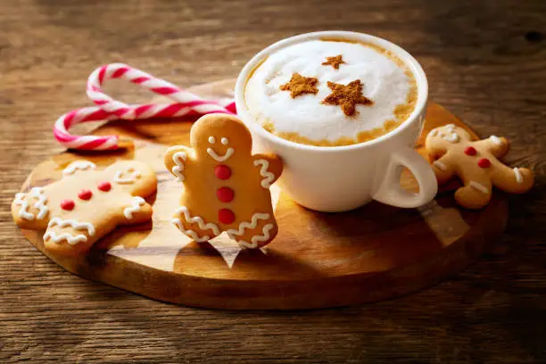Photo of Christmas drink. Cup of cappuccino coffee with stars drawing and gingerbread cookie