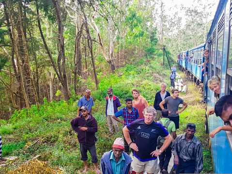 Typical accident in Sri Lanka during a journey in train, a tree trunk felt on the railroad track. Tourists and locals are helping and watching in July 2018