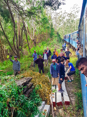 Typical accident in Sri Lanka during a journey in train, a tree trunk felt on the railroad track. Tourists and locals are helping and watching in July 2018