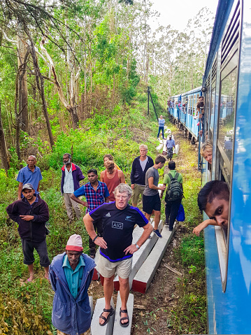 Typical accident in Sri Lanka during a journey in train, a tree trunk felt on the railroad track. Tourists and locals are helping and watching in July 2018