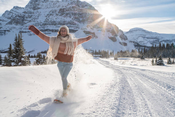 mädchen schneeschuhwandern in verschneiten bergen bei sonnenuntergang spaß haben und genießen winterurlaub - winter snowshoeing running snowshoe stock-fotos und bilder