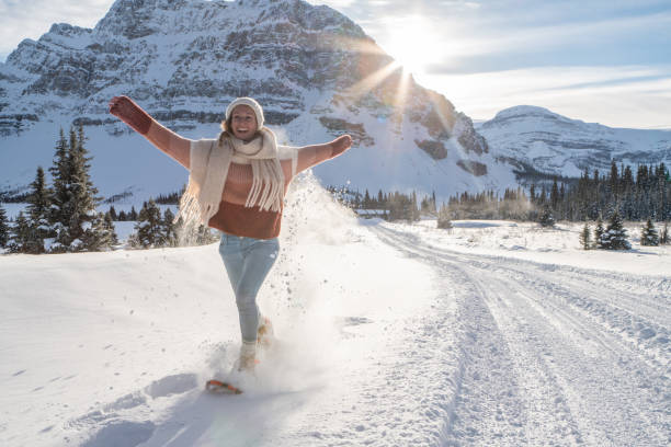 chica raquetas de nieve en las montañas nevadas al atardecer divirtiéndose y disfrutando de las vacaciones de invierno - winter snowshoeing running snowshoe fotografías e imágenes de stock