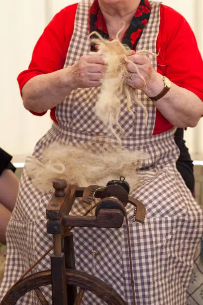 Photo of a elderly woman that spinning wool