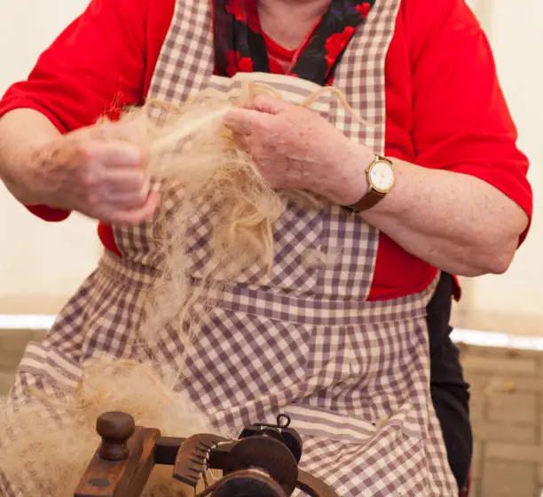 Photo of a elderly woman that spinning wool