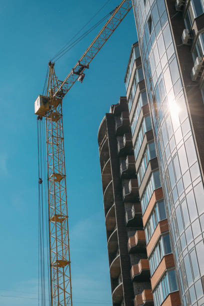 istock Building under construction and construction crane against blue sky and bright sun on summer day. Bottom view. 1176414668
