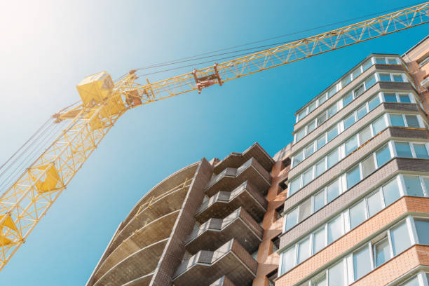 istock Building under construction and construction crane against blue sky and bright sun on summer day. Bottom view. 1176414680