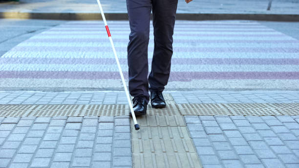 Visually impaired man using tactile tiles to navigate city, finishing crossroad Visually impaired man using tactile tiles to navigate city, finishing crossroad accessibility for persons with disabilities photos stock pictures, royalty-free photos & images