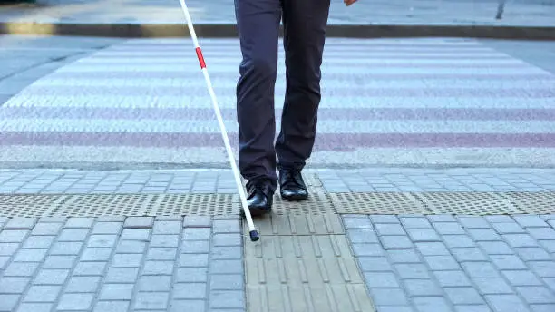 Photo of Visually impaired man using tactile tiles to navigate city, finishing crossroad