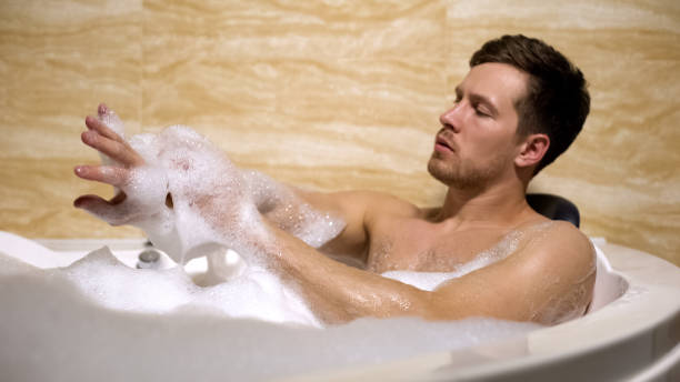 istock Scrupulous man soaping himself with loofah, taking bath with foam, cleanness 1176425410