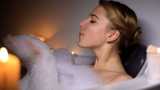 istock Cute woman in bath blowing bubbles, having fun, evening relaxation with candles 1176425554