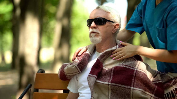 istock Caring nurse covering blind pensioner with blanket outdoors, home for elderly 1176425604