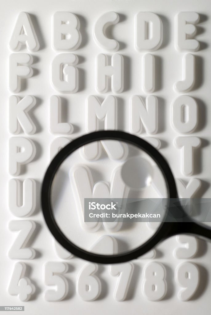 Magnifying glass emphasizing letter ''w'' on white alphabet sheet  Illiteracy Stock Photo