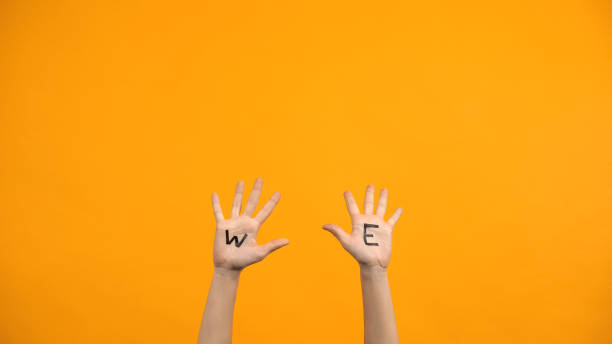 istock We written palms on orange background, volunteers raising hands, togetherness 1176426507