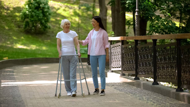 istock Granddaughter supporting disabled grandma with walking frame, day in park 1176426724