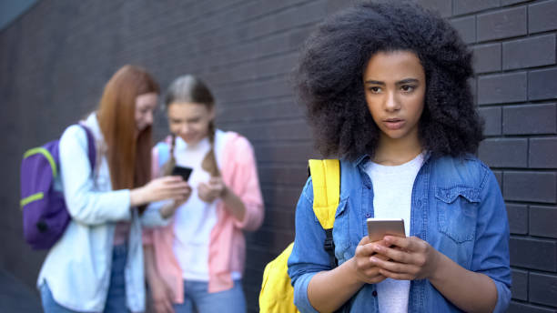 estudante africana triste que lê a mensagem humilhando, embaraço bullying do cyber - rudeness whispering gossip humor - fotografias e filmes do acervo