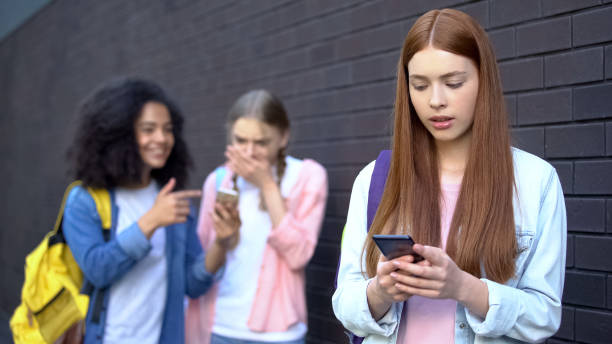 bullied studentin liest peinliche nachrichten soziale netzwerke per smartphone - rudeness whispering gossip humor stock-fotos und bilder