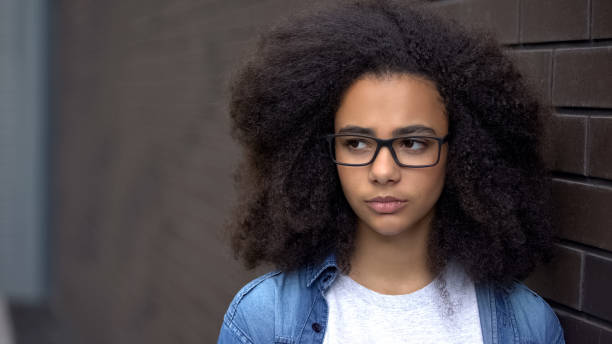 Thoughtful african schoolgirl brick wall background, awkward age insecurities