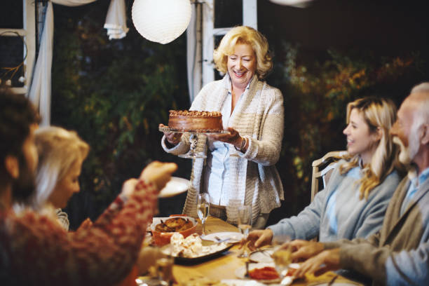 Family celebrating Thanksgiving together. Senior woman serving chocolate cake to her family.