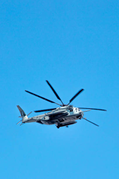 San Diego, California, USA - September 28, 2025: A detailed view of a US Marine Corps CH-53E Super Stallion heavy-lift helicopter transporting an M777 howitzer artillery piece using an external sling load.