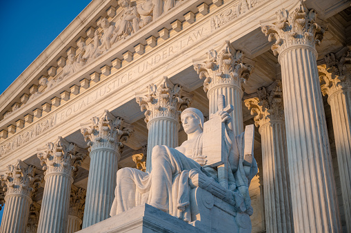 Sunset glow illuminated statue and colonnade of US Supreme court in Washington DC< USA