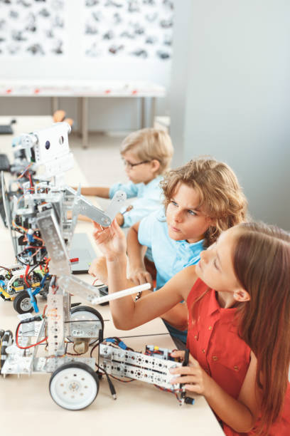 istock Robotics. Children sitting having class fixing robot concentrated 1176439879