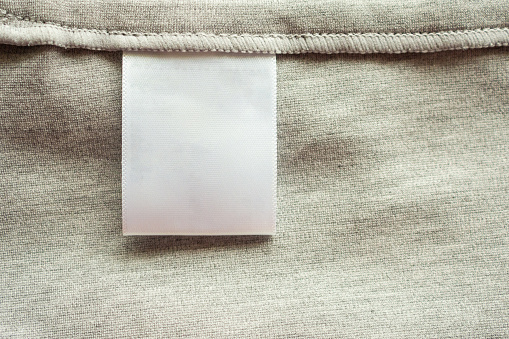 White blank laundry care clothing label on gray fabric texture background