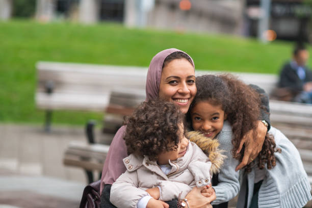 istock Muslim mother hugging daughters in city park 1176440265