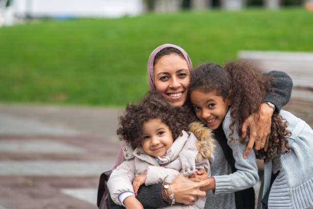 istock Muslim mother hugging daughters in city park 1176440276
