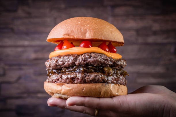 istock Double craft beef burger with cheddar cheese, caramelized onionand pepper pout on wood table and rustic background 1176440541