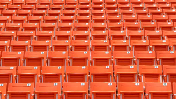 fileiras do assento do estádio na arena dos esportes para o futebol ou o jogo de futebol, teatro público, anfiteatro da sala de concertos com a cadeira vermelha vazia da audiência para o fundo recreativo desportivo ao ar livre - rowing team sport team sport rowing - fotografias e filmes do acervo