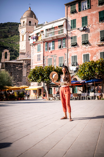 Female tourist checking a map at the main square of a little town in Cinque Terre, Italy