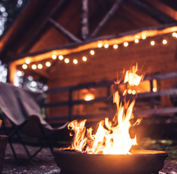 feu de camp de fin de soirée devant une cabane en bois rond - barbecue grill focus outdoors horizontal photos et images de collection