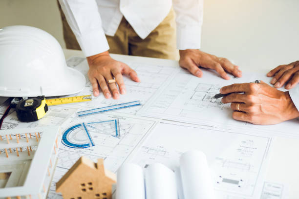 istock Architects working with blueprints and discussing project together at the meeting in the office. 1176463870