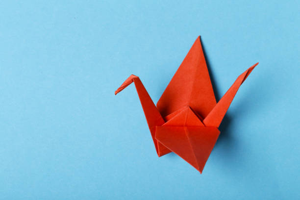 single orange origami paper crane on white background with copy spacestudio shot with NIKON D500