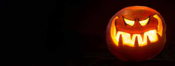 Halloween pumpkin smile and scrary eyes for party night. Black background wide mockup