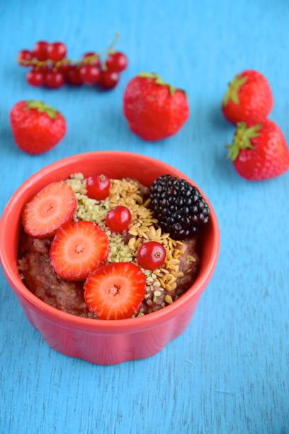 chocolate oatmeal porridge with strawberry, blackberry, red currant, bee pollen, hemp seeds, flax seeds and chia seeds on blue background - blackberry currant strawberry antioxidant imagens e fotografias de stock