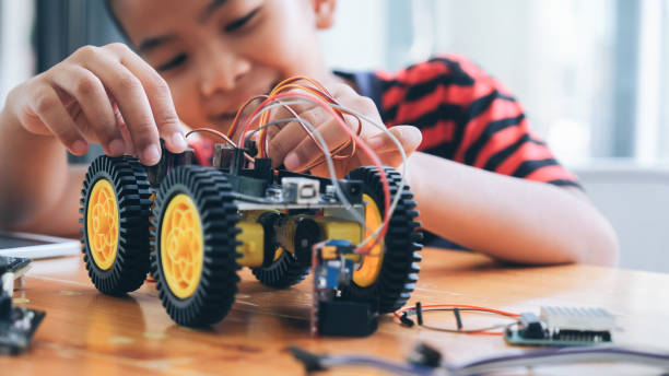 Concentrated boy creating robot at lab. Working on Handmade car model, construction on electronic. Concentrated boy creating robot at lab. Early development, diy, innovation, modern technology concept. stem topic stock pictures, royalty-free photos & images